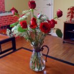 Vibrant red roses in a glass vase on a wooden table.