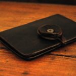 Elegant black leather wallet with decorative flower clasp.