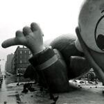 Giant Donald Duck balloon on a city street, black and white photo.