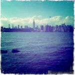 Manhattan skyline with iconic buildings under a sunny sky.