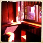 Cozy cafe corner with wooden seating and sunlight.