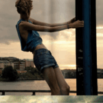 Model poses dramatically against a sunset by the river.