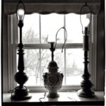 Classic lamps and decorative vase on a window sill, black and white.