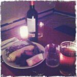 Intimate dinner with wine, steak, corn, and candles.