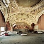 Abandoned theatre ceiling with cars, showcasing faded grandeur.