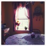 Cozy dining room with floral decorations and sunlight streaming in.