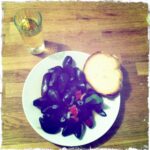 Plate of mussels with bread and a glass of white wine.