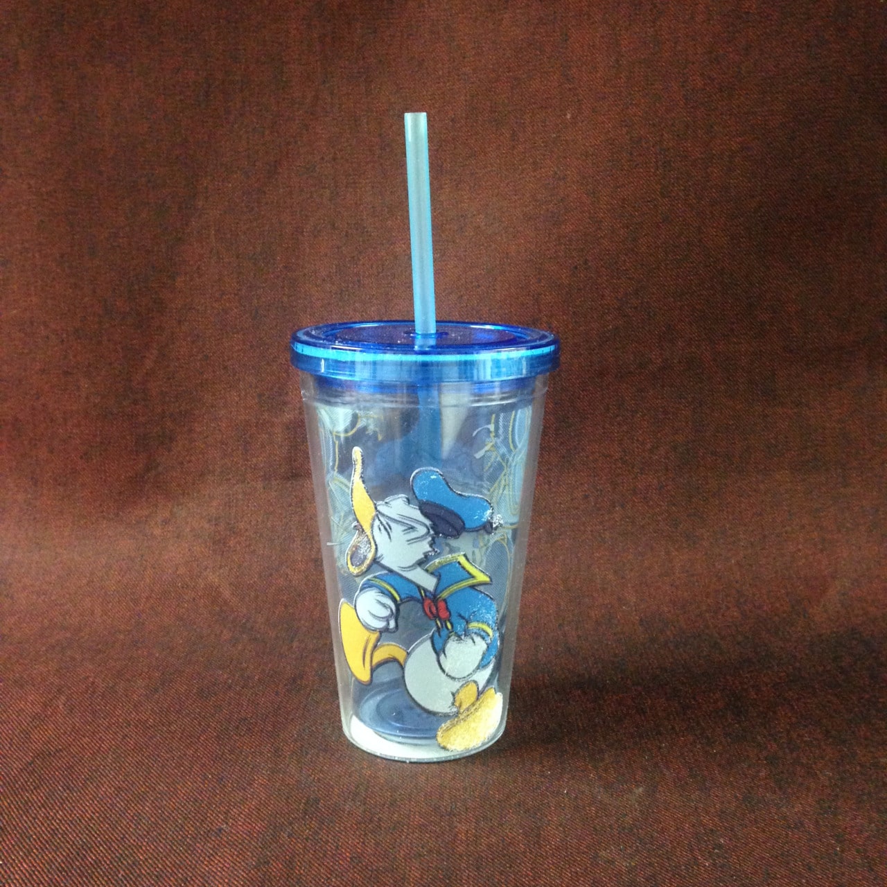 Clear cup featuring Donald Duck with a blue straw.